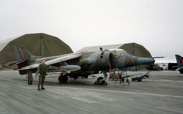 Falkland-szigetek, Stanley repülőtér 1984, 1453-as járat, Harrier GR3 'L'. A háttérben „T” hamarosan lezuhant a kikötőben egy repülőtéri támadás során. A fotó Pete Butt jóvoltából