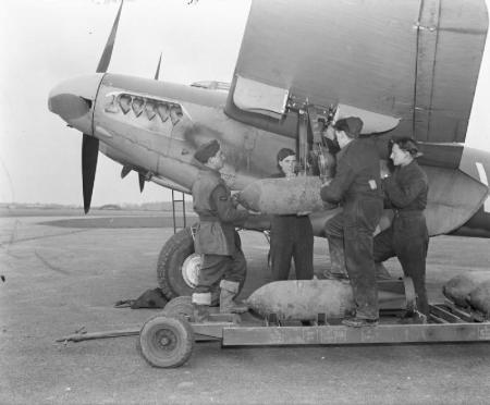 Оружейники вручную подвозят 500-фунтовую бомбу MC к точке загрузки крыла на Mosquito FB Mark VI, MM403 'SB-V', 464-й эскадрильи RAAF в Хансдоне, Хартфордшир.